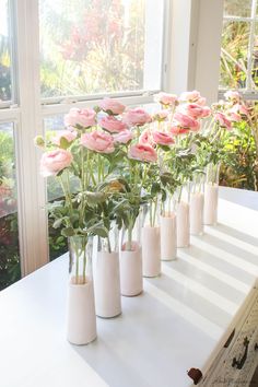 there are many vases with pink flowers in them on the table by the window