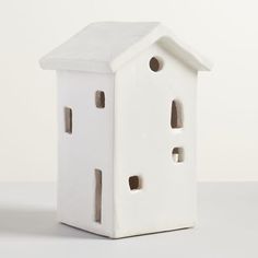 a white ceramic birdhouse with holes in the roof