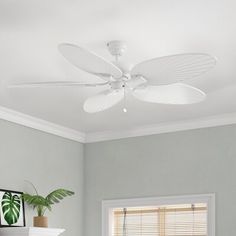 a white ceiling fan sitting above a bed in a room with gray walls and furniture