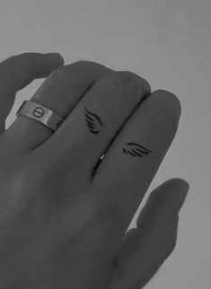 two rings with wings on them sitting next to each other in the middle of their fingers