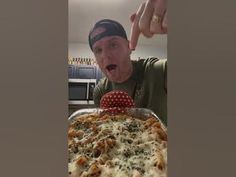 a man making a funny face while looking at a casserole dish on the table