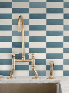 a kitchen sink sitting under a faucet in front of a blue and white checkered wall