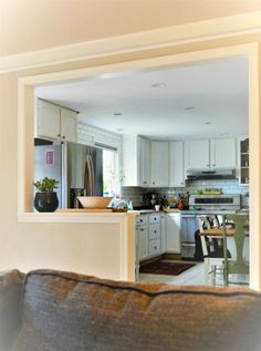 an open kitchen and living room are reflected in the mirror on the wall above the couch