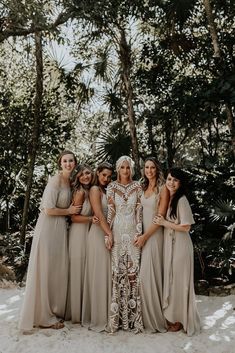 a group of women standing next to each other on top of a sandy ground with trees in the background