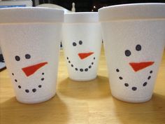 three frosty cups with faces painted on them are sitting on a table next to a laptop