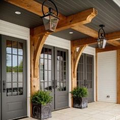 the front porch is decorated with potted plants and two large lanterns on each side