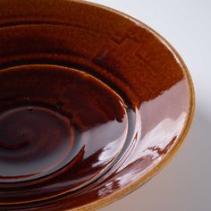 a brown bowl filled with liquid on top of a white table