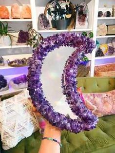 a woman holding up a large purple object in front of a shelf filled with other items