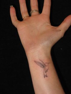 a person's hand with a small bird tattoo on the middle of their palm