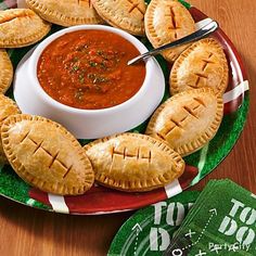 some pies on a plate with a bowl of sauce