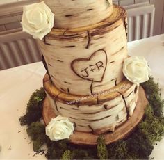 a wedding cake made to look like a tree trunk with white roses on the side