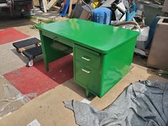 a green desk sitting on top of a pile of junk