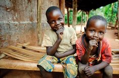 two young boys sitting on a bench smiling