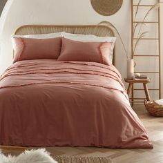 a bed with pink sheets and pillows in a room