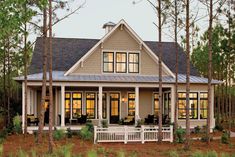 a green and white house with lots of windows on the front porch, surrounded by trees