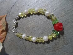 Handmade Beauty and the Beast bracelet Crystals mix, original design, Crystals beads in yellow Mixed with white glass pearls,  With a detail of a small red acrylic flower and two green glass beads similar to the green leaves of the flower, it has a silver tone lobster clasp. This yellow crystal bead bracelet mixed with glass beads is ideal for our princesses' daily wear or for their Beauty and the Beast theme birthday celebration. Green Plastic Bracelet Jewelry, Flower Shaped Plastic Jewelry As Gift, Flower-shaped Plastic Jewelry As Gift, Flower-shaped Plastic Jewelry Gift, Plastic Flower-shaped Jewelry For Gifts, Plastic Flower-shaped Jewelry As A Gift, Green Plastic Beaded Bracelets As Gift, Green Plastic Jewelry For Gifts, Handmade Green Plastic Beaded Bracelets