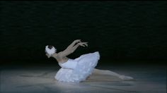 a ballerina in white is performing on the floor with her arms outstretched and legs spread out