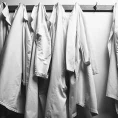 three white coats hanging on a coat rack