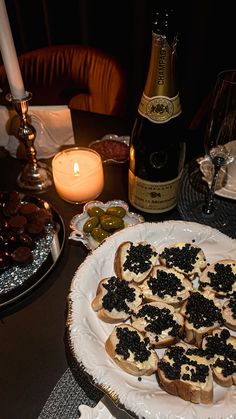 an assortment of appetizers on a plate with candles and wine in the background