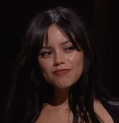 a close up of a person with long hair and wearing a black top, looking at the camera