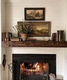 a fire place in a living room with a painting on the wall and pictures above it