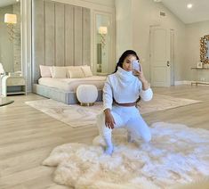 a woman taking a selfie in the living room with white furniture and fur rugs