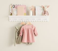 a baby's clothes hanging on a white shelf