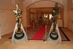 two statues on pedestals in the middle of a room with red carpet and white walls