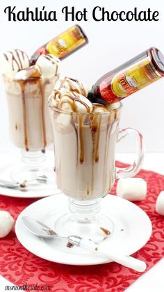 two glasses filled with hot chocolate and marshmallows on a red place mat