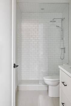 a white toilet sitting next to a walk in shower