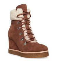 a pair of brown boots with laces and fur on the top, in front of a white background