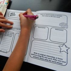 a child is writing on a book with a pen and paper in front of her