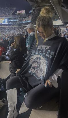 a woman sitting on the bleachers at a football game