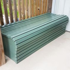 a green bench sitting on top of a porch next to a wooden fence and door