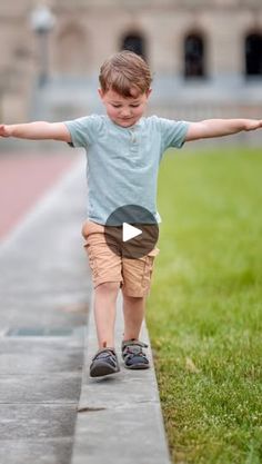 a little boy walking down the sidewalk with his arms outstretched