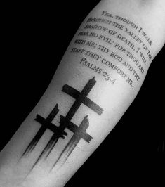 a black and white photo of a cross with the bible verse tattooed on it's arm