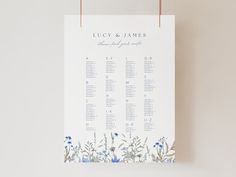 a wedding seating chart hanging on a wall next to a vase with flowers in it