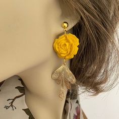 Introducing these exquisitely handcrafted Yellow Rose Clay Earrings, the perfect accessory for adding a touch of elegance to your outfit. Each pair is carefully made with attention to detail, ensuring a truly unique and beautiful piece. The brass accent adds a touch of sophistication, enhancing the overall design. With their delicate charm and undeniable beauty, these handmade earrings are sure to become a cherished addition to your jewelry collection. Made with 6mm gold plated stainless steel hypoallergenic posts.    Each earring is a one-of-a-kind handcrafted piece and is lightweight.  Care instructions:  Avoid using aerosol products, perfumes, jewelry cleaners or chemicals near the jewelry. Clean with a soft damp cloth or baby wipe.  Keep jewelry away from sharp objects to avoid scratch Elegant Adjustable Rose Design Earrings, Elegant Rose Jewelry With Handmade Flowers, Polymer Clay Flower Earrings For Gift, Handmade Flower Earrings As Feminine Gift, Handmade Feminine Flower Earrings For Gifts, Feminine Handmade Flower Earrings For Gift, Elegant Flower Charm Clip-on Earrings As Gift, Flower-shaped Polymer Clay Earrings, Gift Polymer Clay Flower Earrings