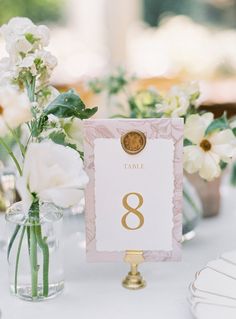 the table numbers are displayed in glass vases with flowers on them, along with plates and napkins