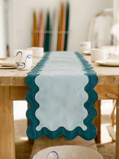 a table with plates and cups on top of it next to a wooden table cloth