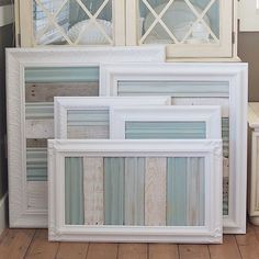 three white frames are stacked on top of each other in front of a wall with windows