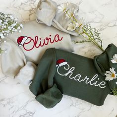 personalized christmas sweater with santa hat and daisies on marble countertop next to flowers