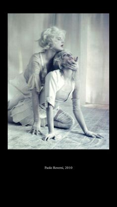 two women are laying on the floor in front of a curtain and one is touching her head