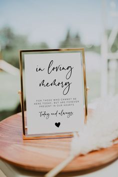 a sign that is on top of a wooden table next to a white and gold feather