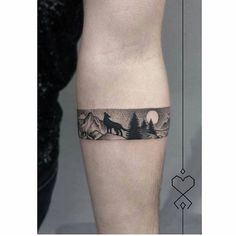 a man's leg with a wolf and trees tattoo on the side of his calf