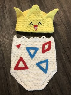 two crocheted hats with different shapes and sizes on top of a wooden table