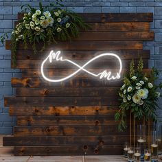 a lighted sign with the word mr and mrs on it next to two vases filled with flowers