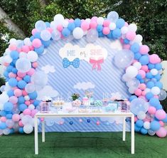 a table topped with balloons and desserts next to a blue wall covered in clouds