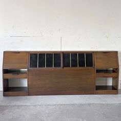 a large wooden shelf with drawers and shelves on it's sides, against a white wall