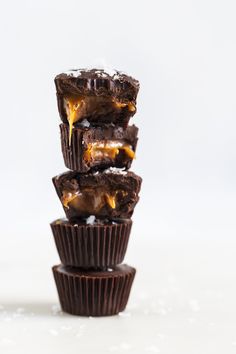 three chocolate cups stacked on top of each other with caramel drizzles